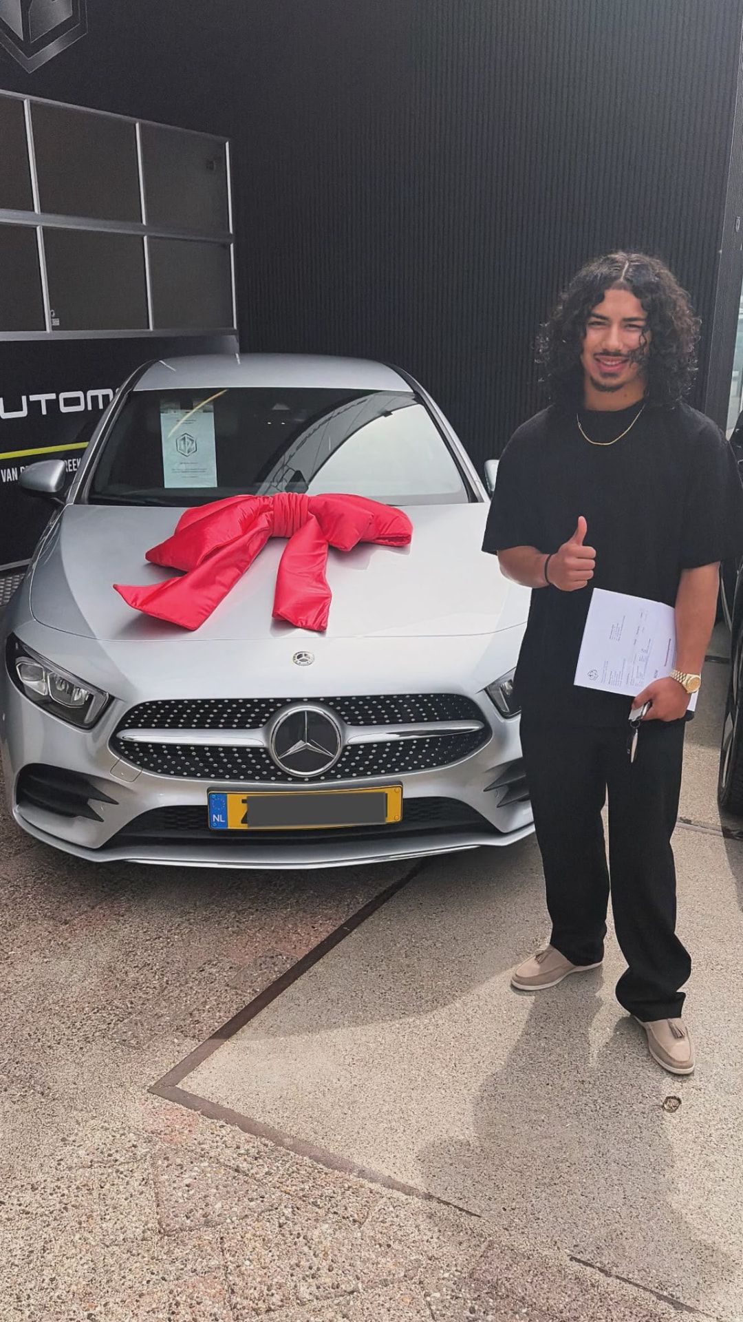 Dave Kreps, rijinstructeur en eigenaar van Rijschool Kreps, staat naast de Mercedes A200 lesauto